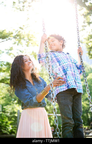 Mutter, Sohn stehen auf Swing Stockfoto