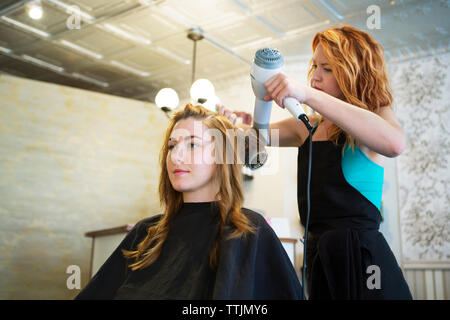 Hairstylist föhnen Kunden Haar im Salon Stockfoto