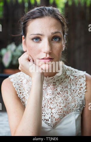 Portrait der Frau mit der Hand am Kinn im Restaurant sitzen Stockfoto