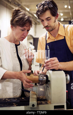 Mann Frau zu unterstützen bei der Gestaltung von Holz in der Werkstatt Stockfoto