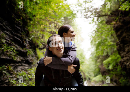 Mann huckepack Freundin beim Spaziergang im Wald Stockfoto