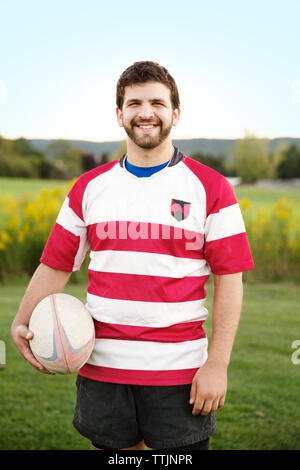 Portrait von glücklichen Spieler, Rugby Ball auf dem Feld gegen den klaren Himmel Stockfoto