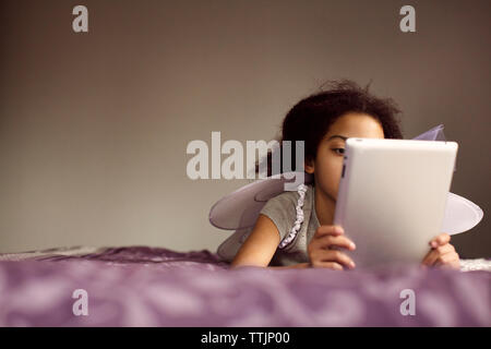 Mädchen in Fairy wings mit Tablet-PC beim liegen auf dem Bett Stockfoto