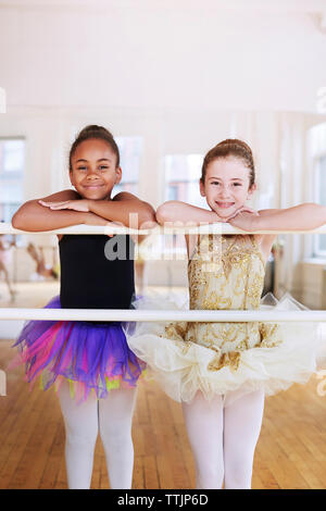 Portrait von lächelnden Ballerinas lehnte sich auf der Stange im Studio Stockfoto