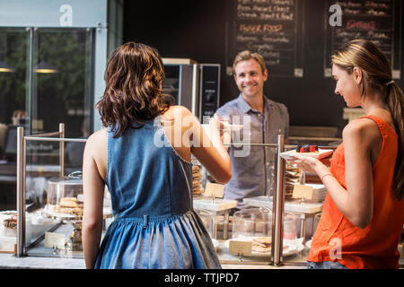 Eigentümer mit Dessert an Kunden im Cafe Stockfoto