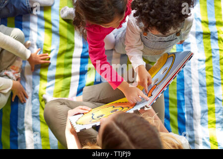 Hohe Betrachtungswinkel und der Lehrer zeigt Bild Buch im Kindergarten Stockfoto