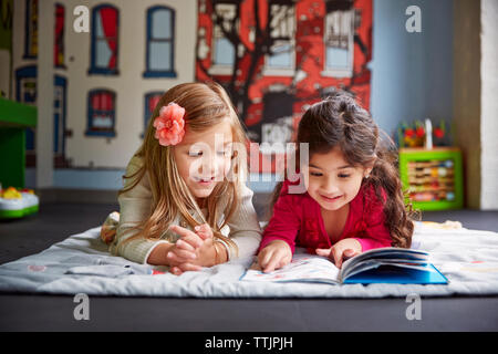 Gerne Freunde lesen Buch, während auf der Decke an der Kinderbetreuung liegen Stockfoto