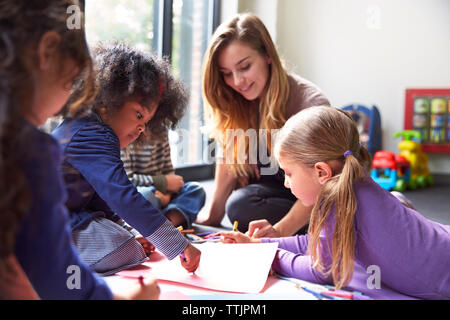 Lehrer und Schüler zeichnen auf Papiere bei der Kinderbetreuung Stockfoto