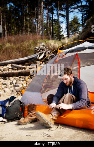 Mann Schuhe tragen, während im Zelt sitzen Stockfoto