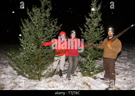 Gerne Freunde Haltewerkzeuge steht man inmitten von Bäumen auf schneebedeckten Feld Stockfoto