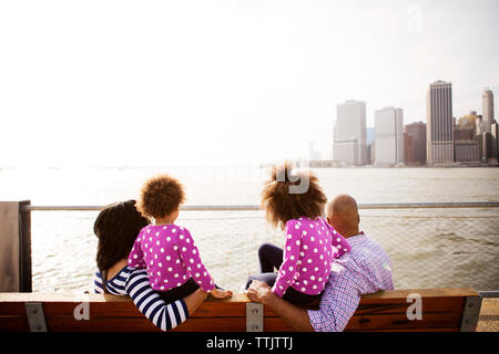 Familie mit Blick auf den Fluss, während sitzt auf der Bank an der Promenade während der sonnigen Tag Stockfoto