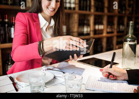 Lächelnd geschäftsfrau am Rechnung, während im Restaurant sitzen Stockfoto