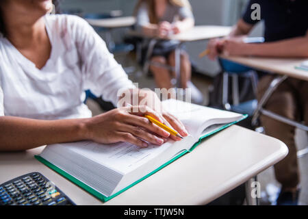 Mittelteil der Frau mit Buch im Klassenzimmer Stockfoto