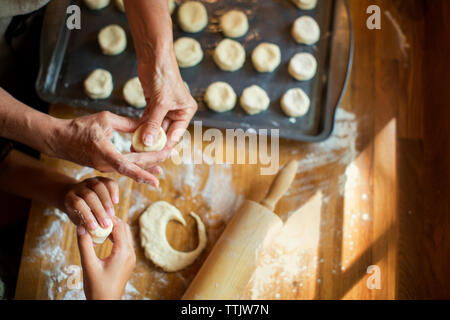 Zugeschnittenes Bild der Enkelin und Oma, die Cookies am Küchentisch Stockfoto