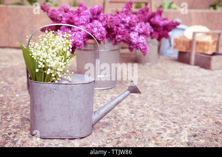 May-Lilies in Gießkanne auf Steinboden. Stockfoto