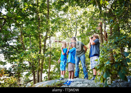 Lehrer, Studenten beim Stehen auf Felsen im Wald während der Exkursion Stockfoto