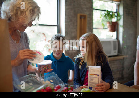Aufgeregte Kinder, Großmutter entfernen essen in der Küche Stockfoto