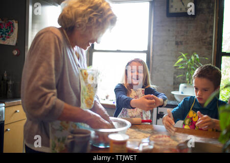 Glückliche Kinder mit Großmutter mischen Mehl in der Küche Stockfoto