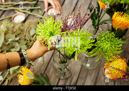 7/8 Bild der Frau, die die Blumen in Töpfen auf Tisch Stockfoto