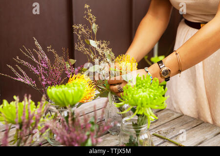 7/8 Bild der Frau, die die Blumen in Töpfen auf hölzernen Tisch Stockfoto