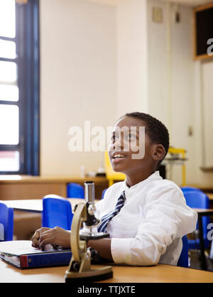 Junge suchen, um sich beim Sitzen am Schreibtisch im Labor Stockfoto