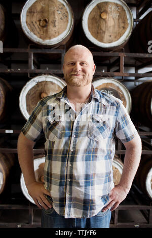 Sicher Mann stand mit den Händen auf der Hüfte gegen Fässer Brauerei Stockfoto