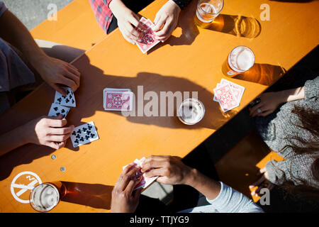 Zugeschnittenes Bild von Freunden Karten spielen und Bier am Tisch in der Brauerei Stockfoto