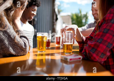 Freunde Bier am Tisch in Brauerei an einem sonnigen Tag Stockfoto