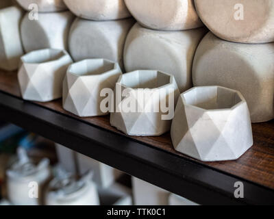Kleine geometrische konkrete Pflanzer auf Holzregal. Leere Beton Töpfe für die Dekoration Stockfoto