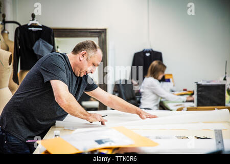 Fashion Designer bei Tisch und arbeiten mit Kollegen im Hintergrund sitzen Stockfoto