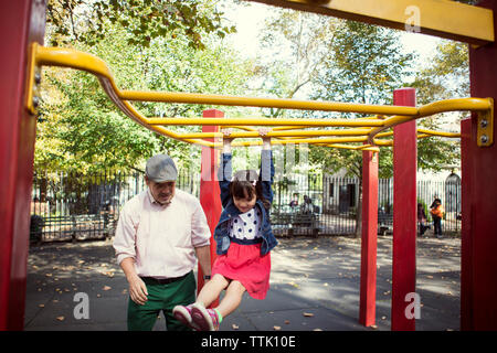 Großvater bei Enkelin hängen an Jungle Gym in Park Stockfoto