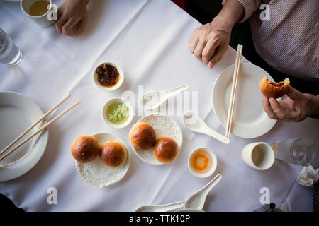 Zugeschnittenes Bild des Menschen bun Holding beim Sitzen am Tisch im Restaurant Stockfoto