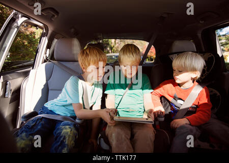 Brüder auf der Suche nach tablet pc im Auto sitzen Stockfoto