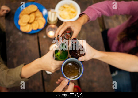 Ansicht von oben der Hände toasten Getränke bei Tisch für Picknick im Wald sitzen Stockfoto