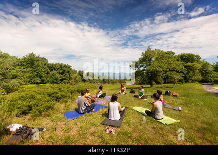 Freunde Ausübung auf Feld gegen bewölkter Himmel Stockfoto