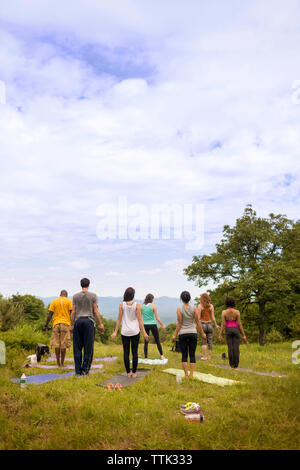 Ansicht der Rückseite des Freunde trainieren beim Stehen auf Feld gegen bewölkter Himmel Stockfoto
