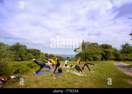 Freunde Ausübung auf Feld gegen bewölkter Himmel Stockfoto