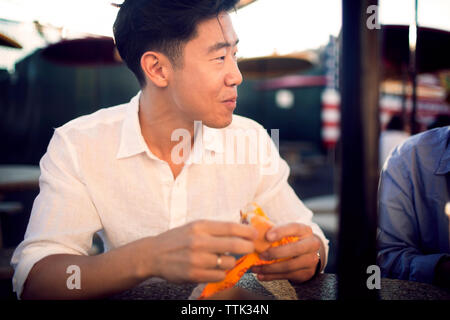 Der Mensch auf der Suche beim Sitzen mit Freundin am Sidewalk Cafe Stockfoto