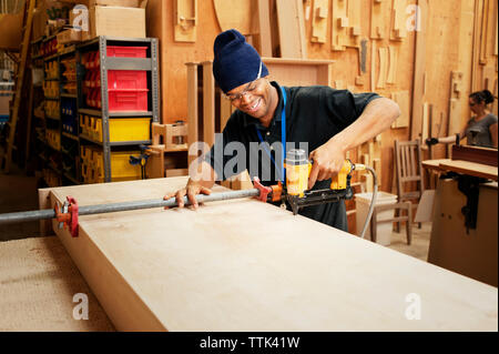 Gerne Tischler bohren Holzbrett in Werkstatt Stockfoto
