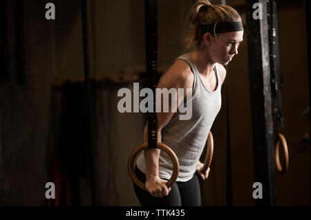 Bestimmt Frau Ausübung auf Gymnastik Ringe im Fitnessstudio Stockfoto