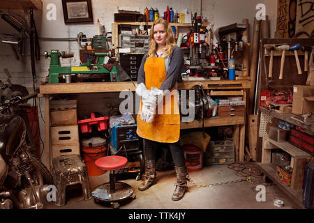 Portrait von zuversichtlich Mechanikerin tragen Schürze in Werkstatt Stockfoto