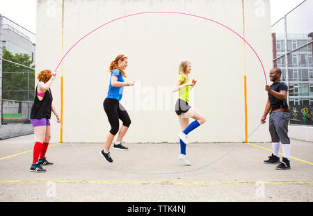 Freunde genießen Double Dutch gegen weiße Wand Stockfoto