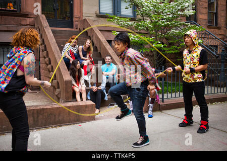 Gerne Freunde auf der Suche nach Mann, double Dutch auf Bürgersteig Stockfoto