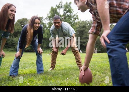 Freunde auf der Suche nach Mann mit Fußball-Ball auf der Wiese Stockfoto