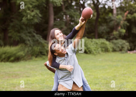 Mann huckepack Frau beim Fußball spielen auf dem Feld Stockfoto