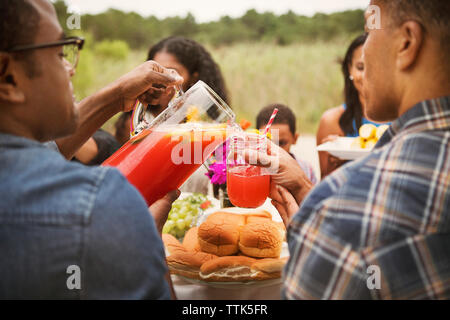 Man gießt Getränk im Glas am Frühstückstisch Stockfoto