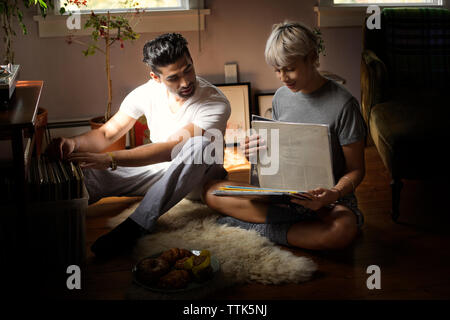 Junges Paar auswählen Schallplatten beim Sitzen auf dem Boden zu Hause Stockfoto