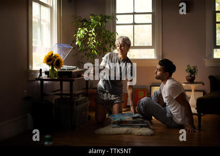 Der Mensch auf der Suche nach woman holding Schallplatte auf dem Boden zu Hause Stockfoto
