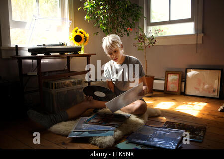 Junge Frau von Schallplatten, während auf dem Boden zu Hause sitzen Stockfoto
