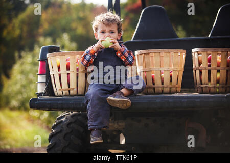 Porträt der jungen das Essen der Frucht beim Sitzen auf Geländewagen. Stockfoto